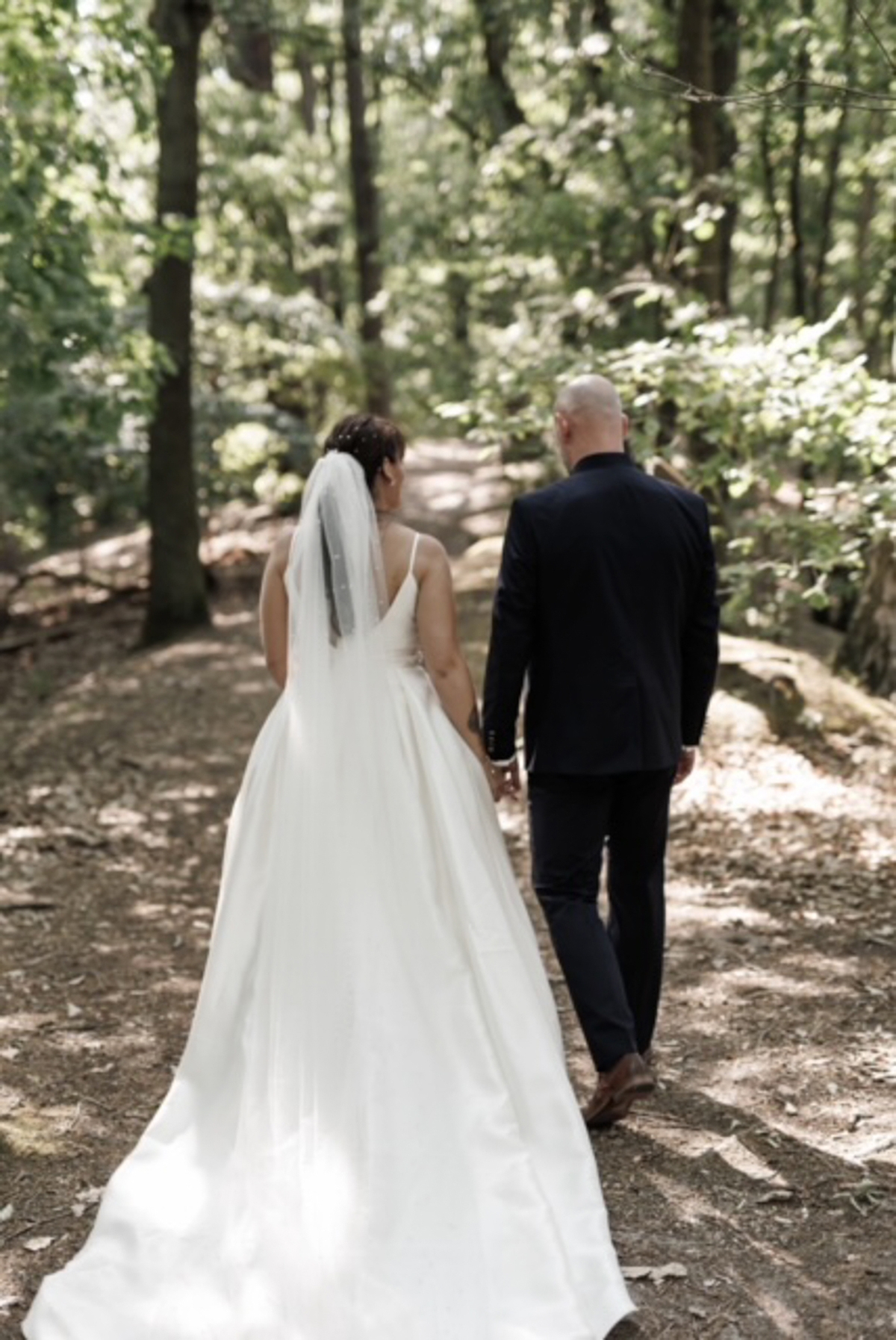 Hochzeitspaar im Wald von hinten mit Schleier